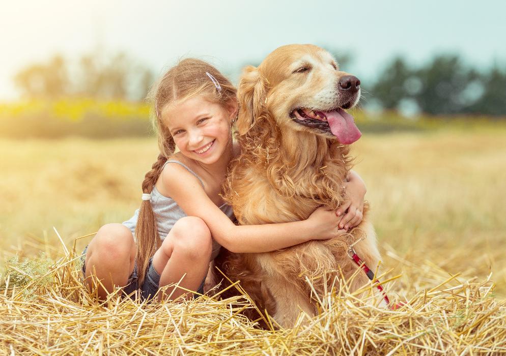 girl hugging dog in field | pediatric dentist spring branch