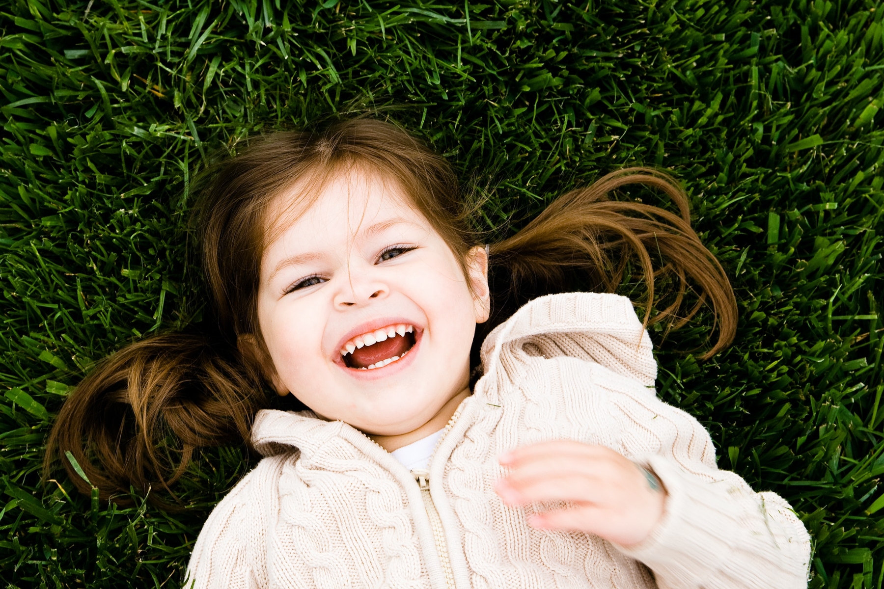young girl laying in grass laughing outside