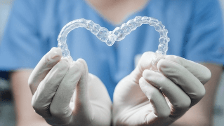 dentist holding clear aligners for Invisalign for kids
