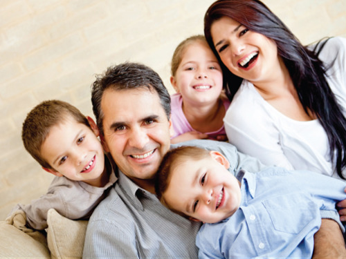 Family of two parents and three children smile for camera